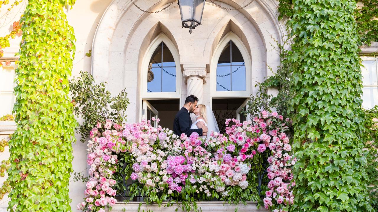 The new bride and groom share a kiss on a balcony after tying the knot. Picture: Kevin Ostajewski/Shutterstock/MEDIA MODE