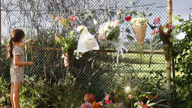 Pictured is a little girl hanging a flower next to other tributes on a pathway leading to Little Bay in Sydney. Simon Nellist was killed in a fatal shark attack there whilst swimming in the bay two days earlier. Picture: Richard Dobson