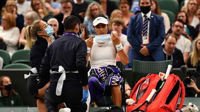 Britain's Emma Raducanu (C) receives medical aid during the match against Australia's Ajla Tomljanovic