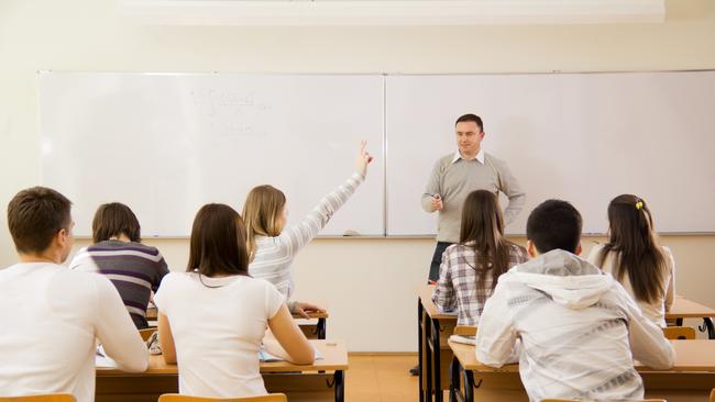 "rear view of high-school students in a classroom, during lesson. Girl responding to teacher's question."