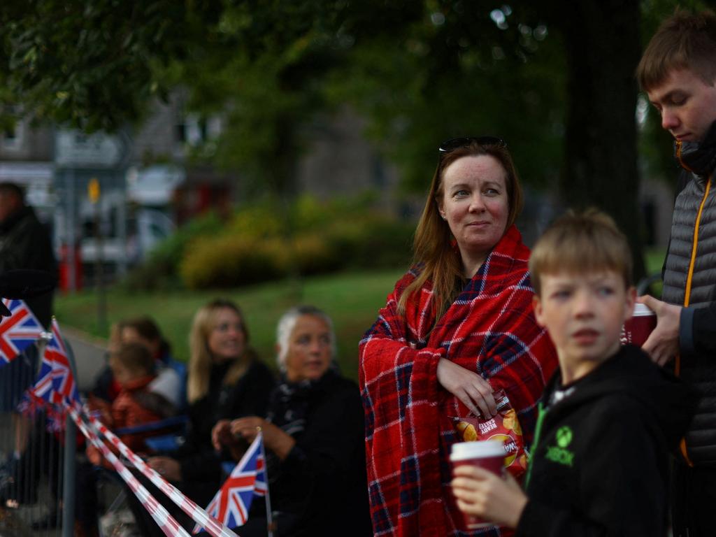 People line the street waiting for the funeral cortege carrying Britain's Queen Elizabeth in the village of Ballater, following the queen's passing, near Balmoral. Picture: Reuters.