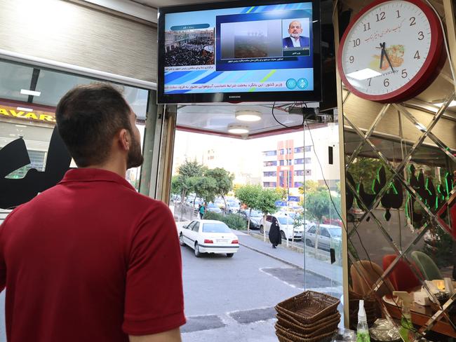 An Iranian man watches the news on TV in a restaurant in Tehran as state TV reported that a helicopter carrying Iran's president was involved in "an accident" in poor weather. Picture: AFP