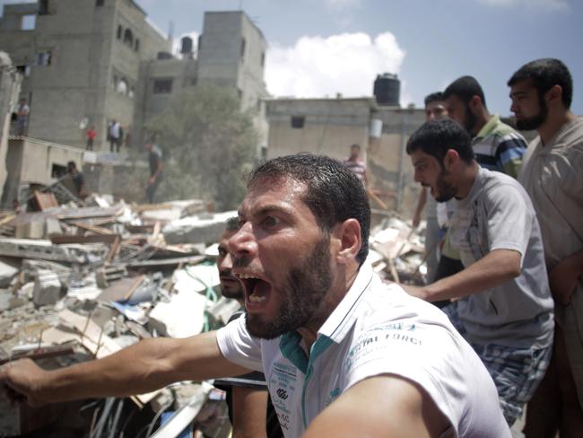 A Palestinian overcome by emotion watches rescuers carry a body from the rubble of a house which was destroyed by an Israeli missile strike in Gaza City on Monday. AP Photo/Khalil Hamra