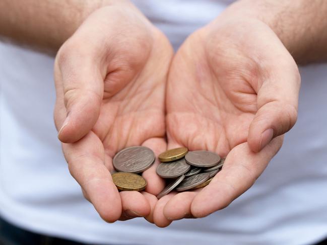 A caucasian man holds out some Australian coins; poor money generic hands