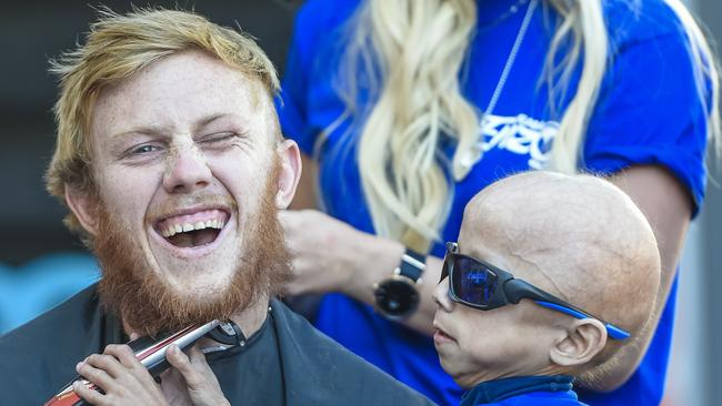 Glenelg footballer Josh Scott getting his head shaved at a charity day to raise money for seven-year-old Enzo Cornejo, who has rapid-ageing condition progeria. Pic.AAP/ Roy VanDerVegt