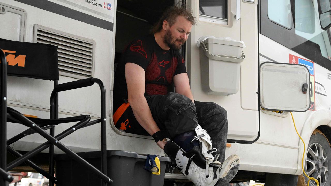 Australian biker Toby Price removes his boots at the end of the stage 13 of the Dakar 2023 between Saybah and al-Hofuf, in Saudi Arabia, on January 14, 2023. (Photo by FRANCK FIFE / AFP)