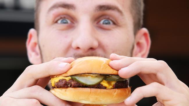 Burger Head co-owner Josh DeLuca tucks into one of his creations. Picture: Bob Barker.