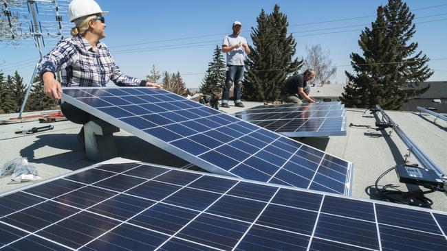 Workers installing solar panels on a residential home’s roof.