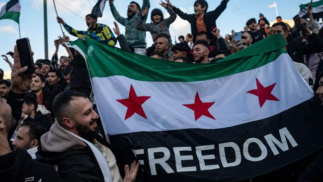 A demonstrator holds a Syrian opposition flag as members of the Syrian community chant slogans in Syntagma square in Athens to celebrate the end of the regime of Syrian dictator Bashar al-Assad.