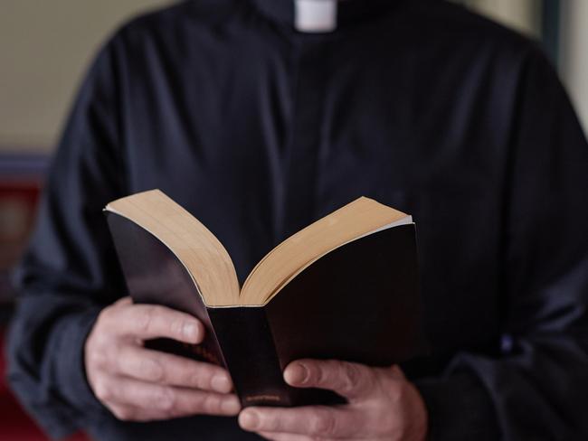 Close-up of priest reading Bible book during ceremony standing near the altar in church