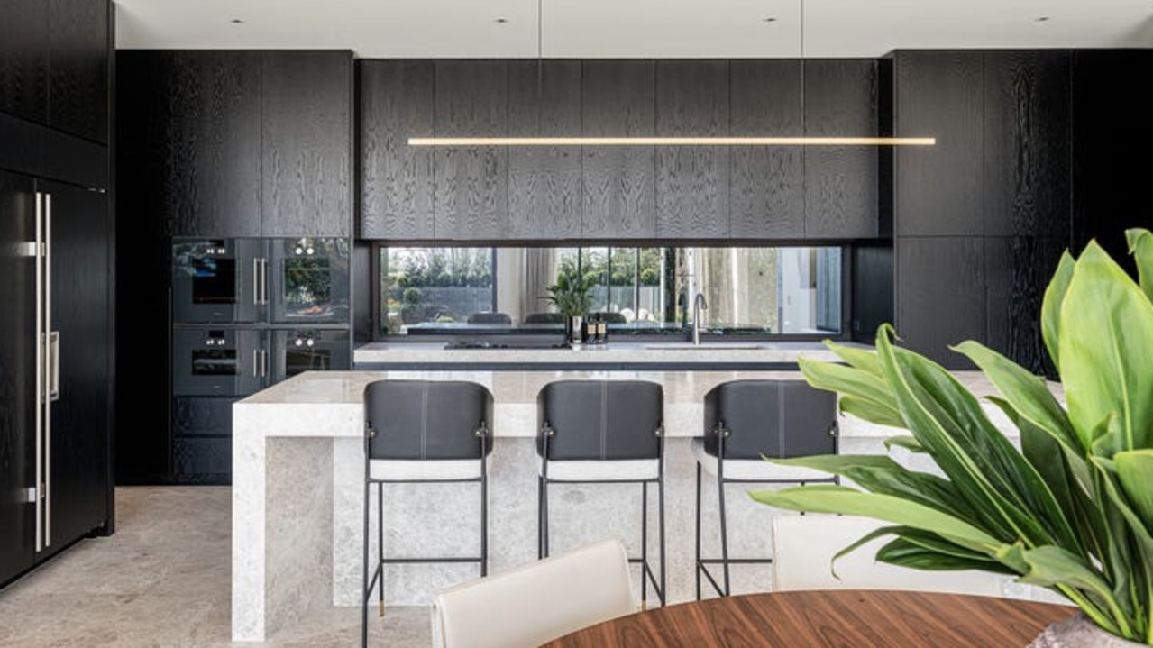 A marble-clad island bench and black American oak veneer cabinetry make a statement of luxury in the kitchen.