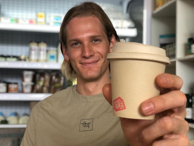 Chris Hayward has opened Veda, an organic fair-trade coffee shop, cafe and grocer on Lawrence St, Freshwater. He is holding a recyclable coffee cup made with sugar cane plant pulp. Picture Julie Cross