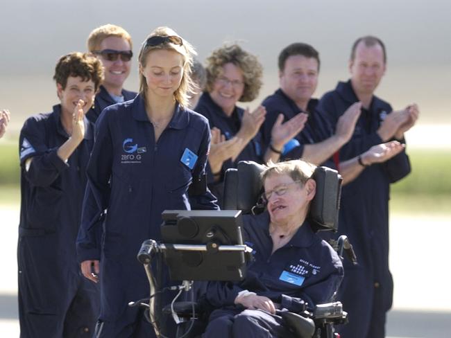 Astrophysicist Stephen Hawking is assisted off the tarmac at the Kennedy Space Center by his caregiver, Monica Guy, as he is applauded by members of the flight crew after completing a zero-gravity flight. Picture: AP