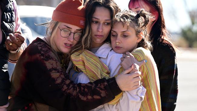 Atlas Pretzeus, left, and her friends hug one another as theytheir respects at a makeshift memorial near Club Q. Picture: Getty Images