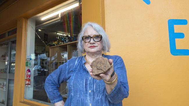 Dawn Sanders standing in front of her business of 30-years, Warehouse 73 Emporium, while holding the rock which smashed her shopfront window. Picture: Floss Adams.
