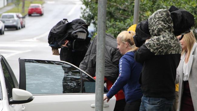 Stephanie Belthikiotis (orange shirt) covers her face as she gets into a car at Wyong Local Court on Tuesday morning. Picture: Fiona Killman