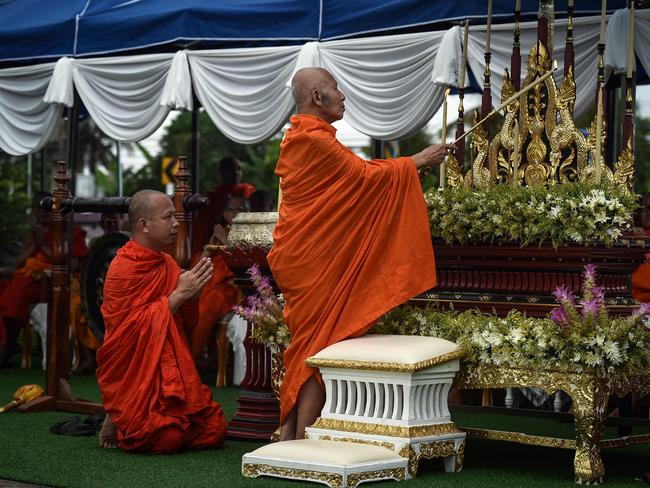 A monk lights a candle at an altar during a Buddhist prayer for the trapped children.