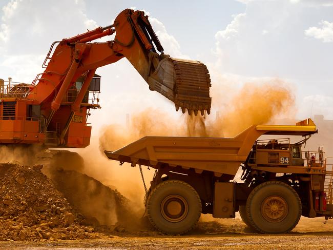 A haul truck is loaded by a digger with material from the pit at Rio Tinto Group's West Angelas iron ore mine in Pilbara, Australia, on Sunday, Feb. 19, 2012. Rio Tinto Group, the world's second-biggest iron ore exporter, will spend $518 million on the first driverless long-distance trains to haul the commodity from its Western Australia mines to ports, boosting efficiency. Photographer: Ian Waldie/Bloomberg via Getty Images