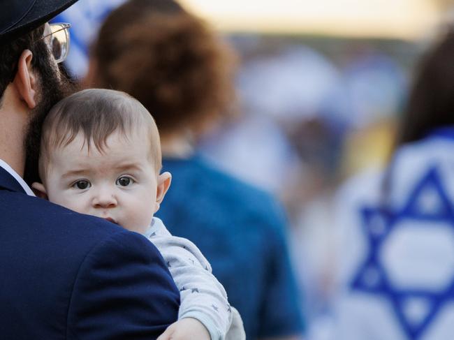 A man holds his baby in the crowd as BrisbaneÃs jewish community held a peaceful gathering in the Roma Street Parklands in support of Israel. Picture Lachie Millard
