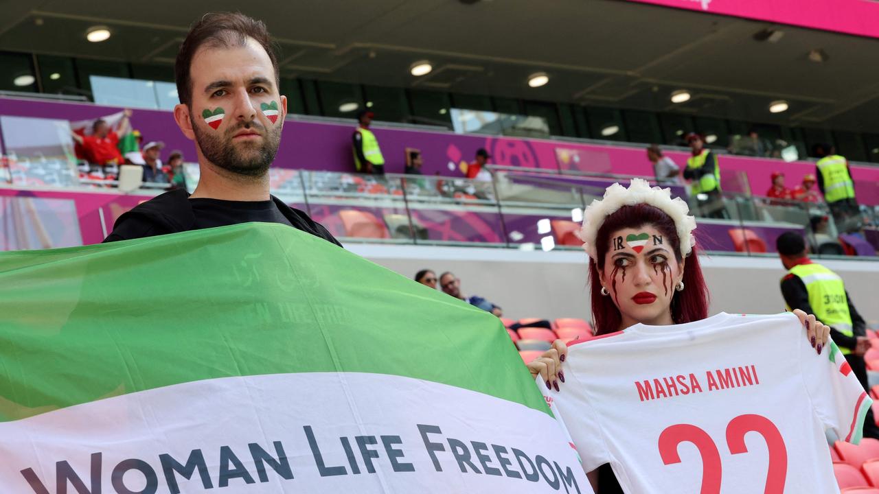 An Iran's supporter with blood tears make up on her face holds a football jersey reading the name of Mahsa Amini.
