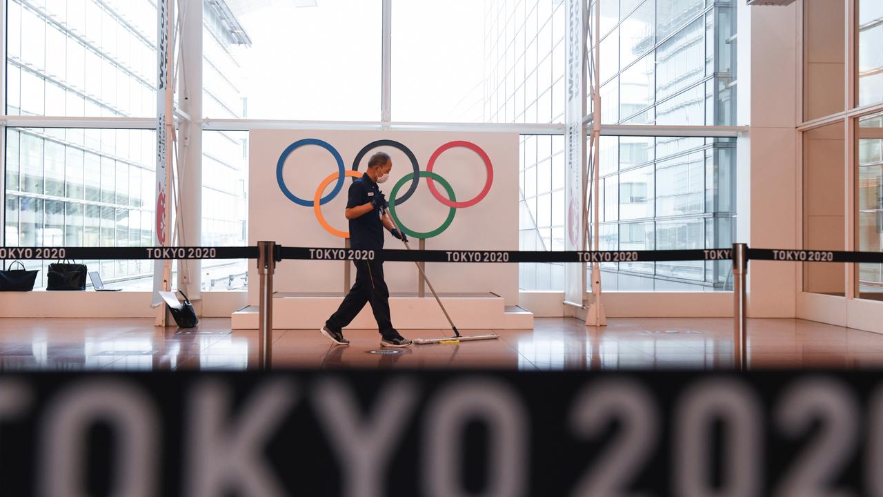 A worker sweeps in front of a banner for the Tokyo 2020 Olympic Games at Haneda Airport in Tokyo this week. Picture: Noriko Hayashi/Bloomberg via Getty Images