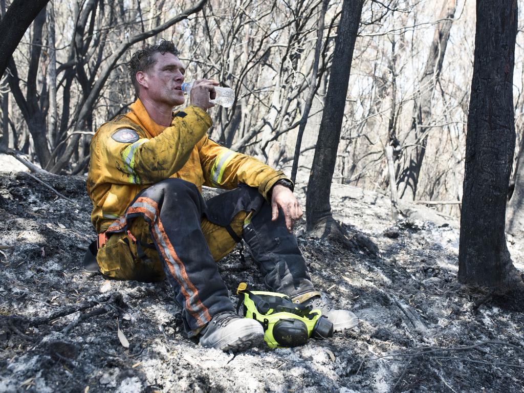 Tasmania Fire Service firefighter Simon Pilkington at the Gell River fire. A soft bed of ash and a spot under some brush is the only refuge when the hourly weather reading showed 38C in the shade. Picture: WARREN FREY/TASMANIA FIRE SERVICE