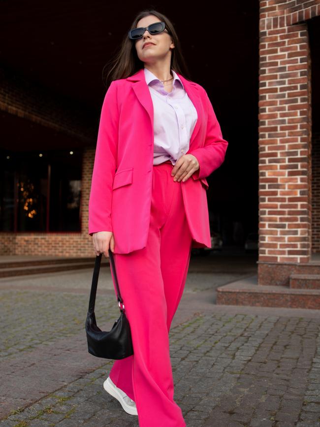 Elegant confident brunette woman in black glasses, a pink suit, a shirt, a black bag. Picture: iStock