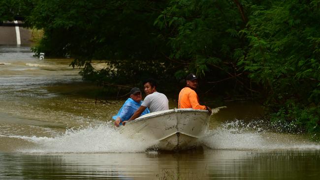 Wet weather in Townsville. Poultry farmer Jeff Ironside brings employees Dennis Bernas and AJ Willis back across the Bohle River, cut by flood water at Allambie Lane. Picture: Evan Morgan
