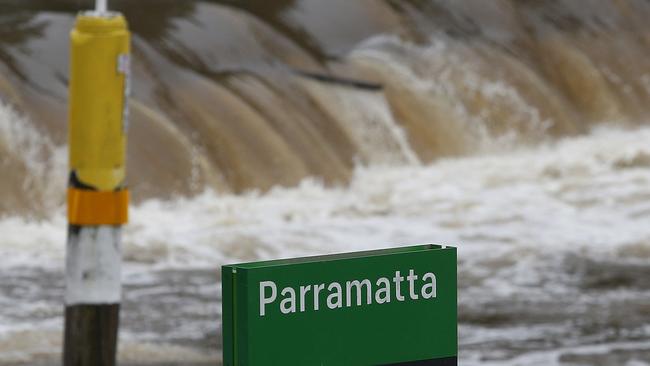 Water from the swollen Parramatta River spills over the weir at the Charles Street Wharf. Picture: John Appleyard