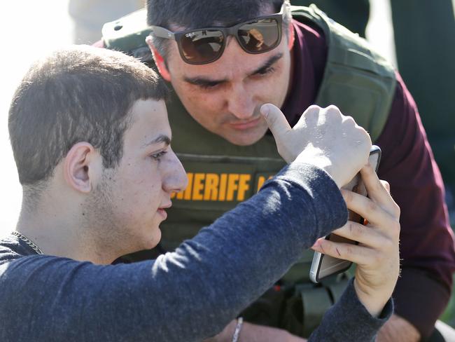 A student shows a law enforcement officer a photo or video from his phone. Picture: AP Photo/Wilfredo Lee