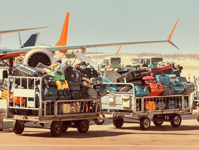 Passengers baggage in carts is waiting to be loaded onto the plane. The concept of damage or loss of tourists luggage