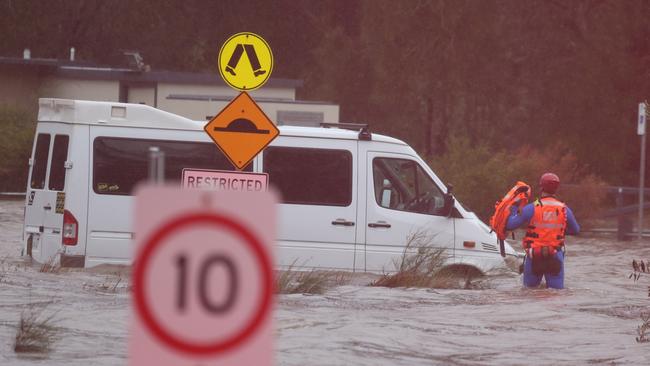 Rescuers check on a car in Narrabeen. There were no occupants inside. Picture: John Grainger