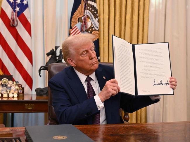 Trump holds up an executive order he just signed in the Oval Office. Picture: Roberto Schmidt