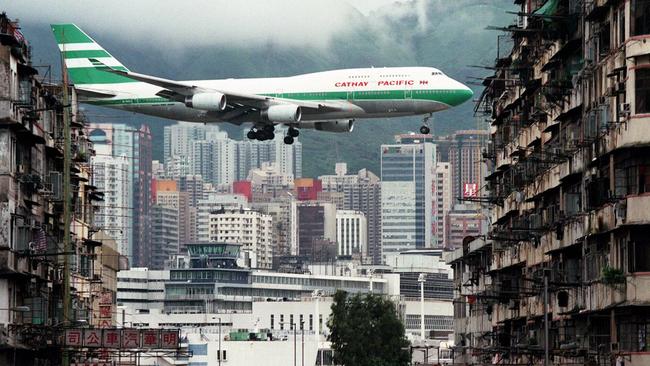 A Cathay Pacific Boeing 747-400 flies over Kai Tak Airport control tower to land.