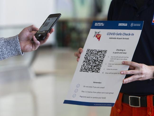 ADELAIDE, AUSTRALIA - Advertiser Photos MAY 7, 2021: SAPOL and SES Officers hold up COVID-SAfe QR Code Check-in for Qantas Passengers at Adelaide Airport on Canberra flight QF725 and are required to use the COVID-SAfe QR Code Check-in contact tracing app as they disembark. COVID 19 reporting and tracking protocols at Adelaide Airport have changed in recent days from the face-to-face counters to  scan check-ins for arrivals at Adelaide Airport, SA. Picture: Emma Brasier