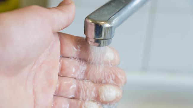 Bad burns on male fingers, cooling hand under tap water.