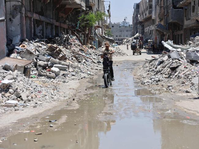 A Palestinian rides his bike past rubble and through open sewage, as garbage collection and any other municipality services come to a halt due to the Israeli bombardment of the Gaza Strip. Picture: AFP