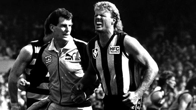 Dermott Brereton helped from field after being decked by Mark Yeates. Picture: CLIVE MACKINNON