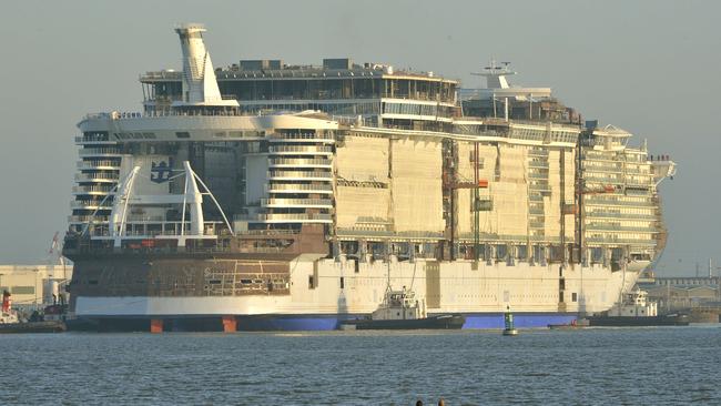 TOPSHOTS Fishing boats pass by as the cruise liner "Harmony of the Seas" is towed by tug boats into its new moorings at the STX Shipyards in Saint-Nazaire on June 19, 2015. The cruise liner, one of the largest ever built, with a capacity of 6,000 passengers is scheduled for delivery in April 2016. AFP PHOTO / GEORGES GOBET