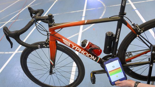 A staff member of the International Cycling Union (UCI) holds a tablet to scan a bicycle.
