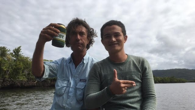 Justin Ward shares a beer and a smoke with one of the suspect asylum-seekers on the Daintree River yesterday.