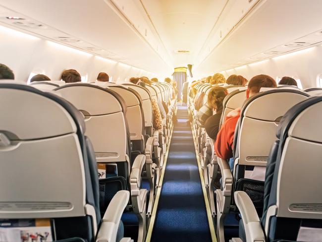 Commercial aircraft cabin with rows of seats down the aisle. morning light in the salon of the airliner. economy class