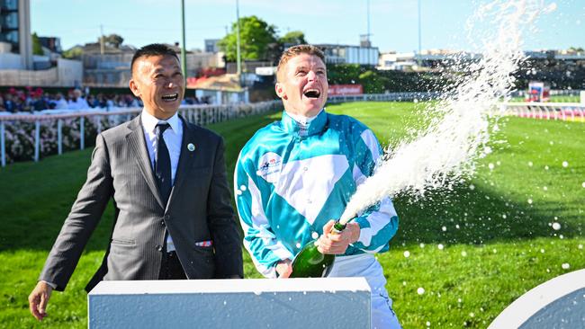 James McDonald sprays the champagne with Romantic Warrior’s trainer Danny Shum. Picture: Vince Caligiuri/Getty Images