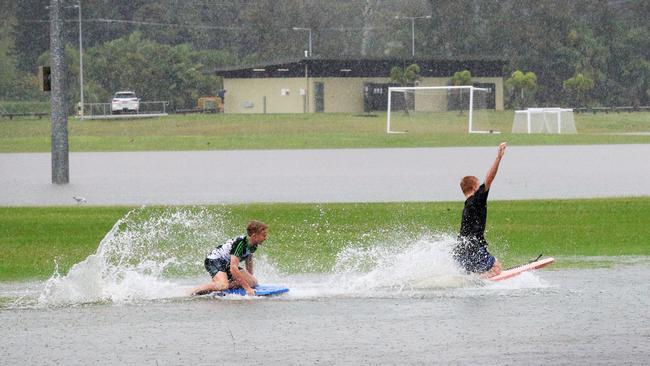 Siblings Ziggy Martin (13) and Poppy Martin (10) watch big brother Kieren Lee (15) make the most of floodwater which swamped their soccer field at Coplicks Sports Park on Tallebudgera Connection Road, Tallebudgera , after torrential rain over night caused the creek to break its banks. NCA NewsWire / Scott Powick