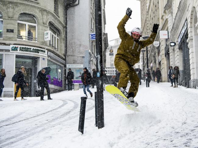 Sylvain rides his snowboard on a snow-covered street during a snowfall in Lausanne, Switzerland, Thursday, March 1, 2018. Picture: AP