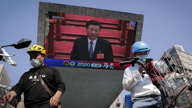 Food delivery workers wearing face masks to protect against the spread of the new coronavirus prepare to delivery foods near a TV screen showing Chinese President Xi Jinping. Picture: AP