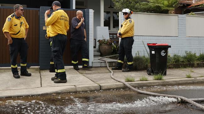 Rural Fire Service volunteers pump water out of a house on Rolfe St, Manly, on Tuesday. Picture: Tim Hunter.