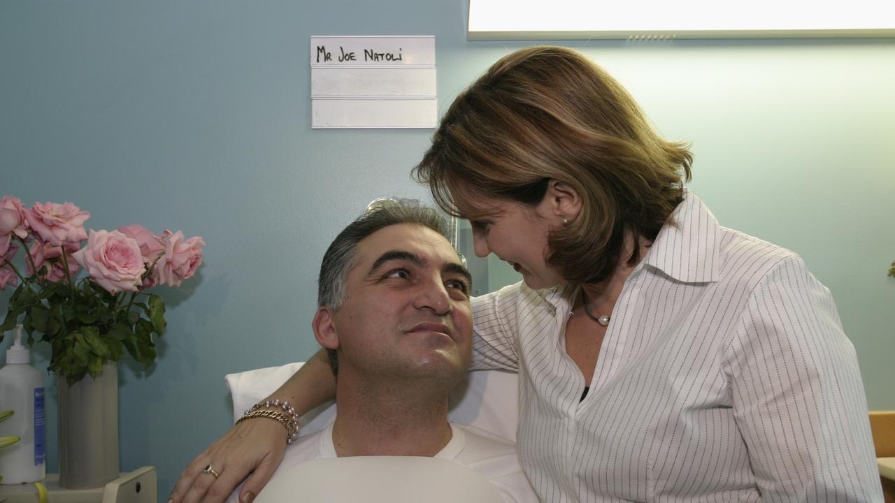 Then mayor Joe Natoli in a hospital bed with wife Rosanna in 2004 after he broke his back in a bull ride for the Daniel Morcombe fundraiser. Photo: David Thomas