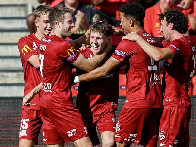 Harry Crawford (centre) is congratulated by his Adelaide United teammates after scoring against Brisbane Roar. Picture: Mark Brake/Getty Images