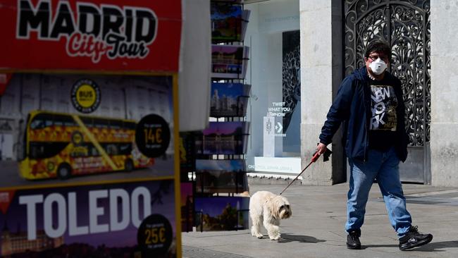 A man wearing a face mask walks his dog in after regional authorities ordered all shops in the region be shuttered for fourteen days save for those selling food, chemists and petrol stations, in order to slow the coronavirus spread. Picture: AFP